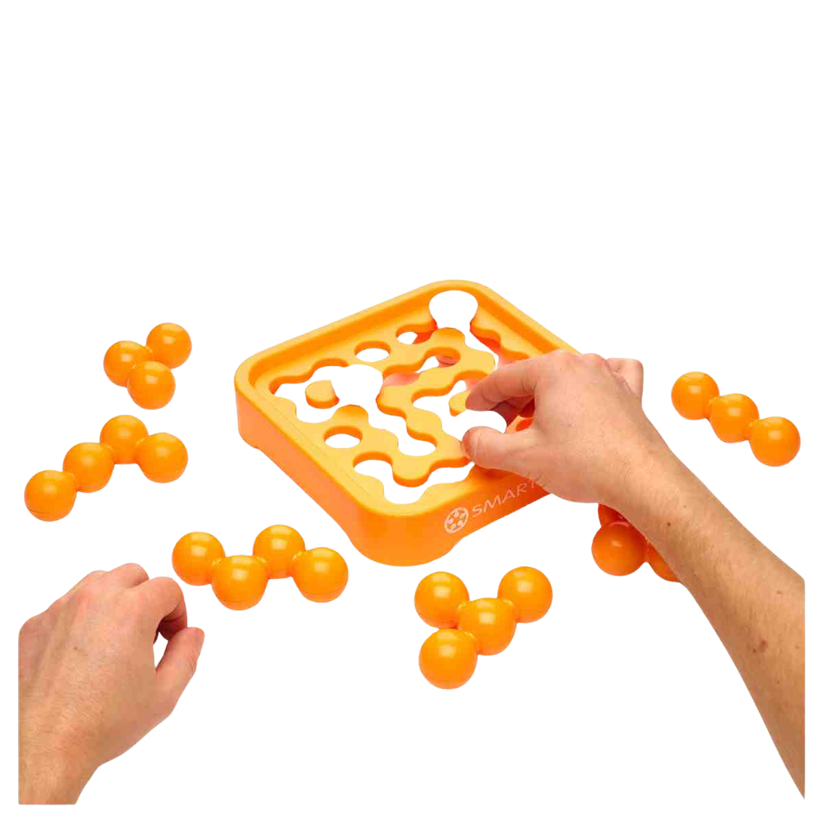 Deux mains placent des boules orange interconnectées dans le plateau carré du jeu de puzzle IQ MINI XXL, en les insérant dans des formes découpées, tandis que plusieurs pièces orange sont éparpillées sur le plateau.